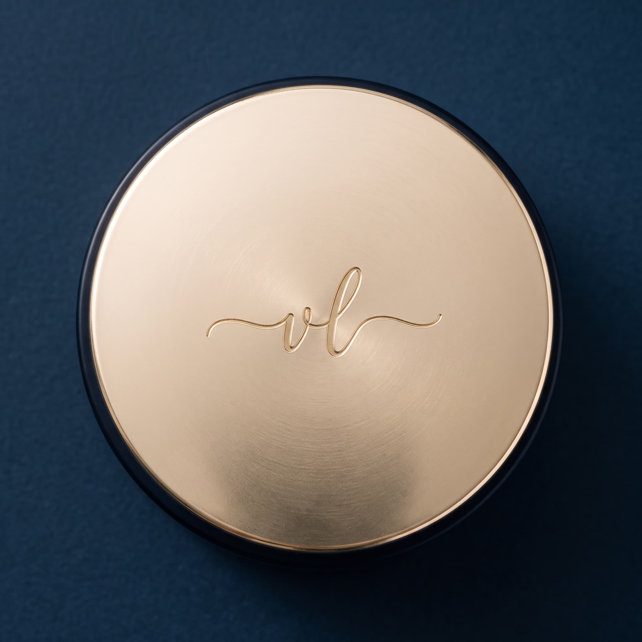 Top-down view of the champagne-gold lid with its engraved vl monogram