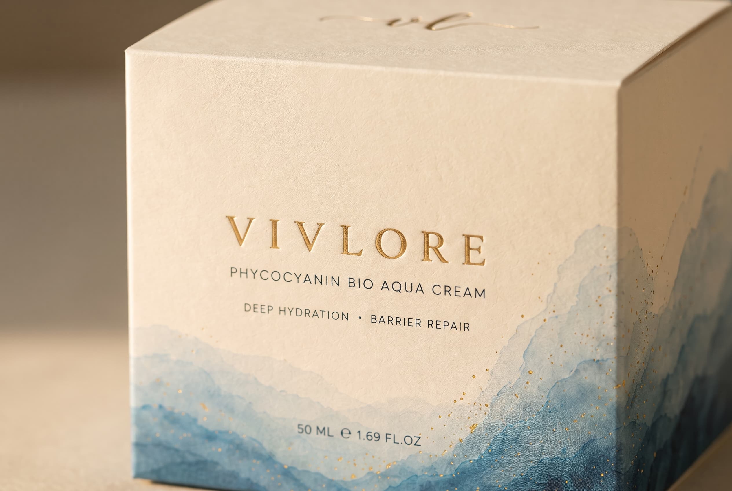 Detail of the ivory box with blue watercolor waves, fine gold flecks and gold VIV LORE lettering